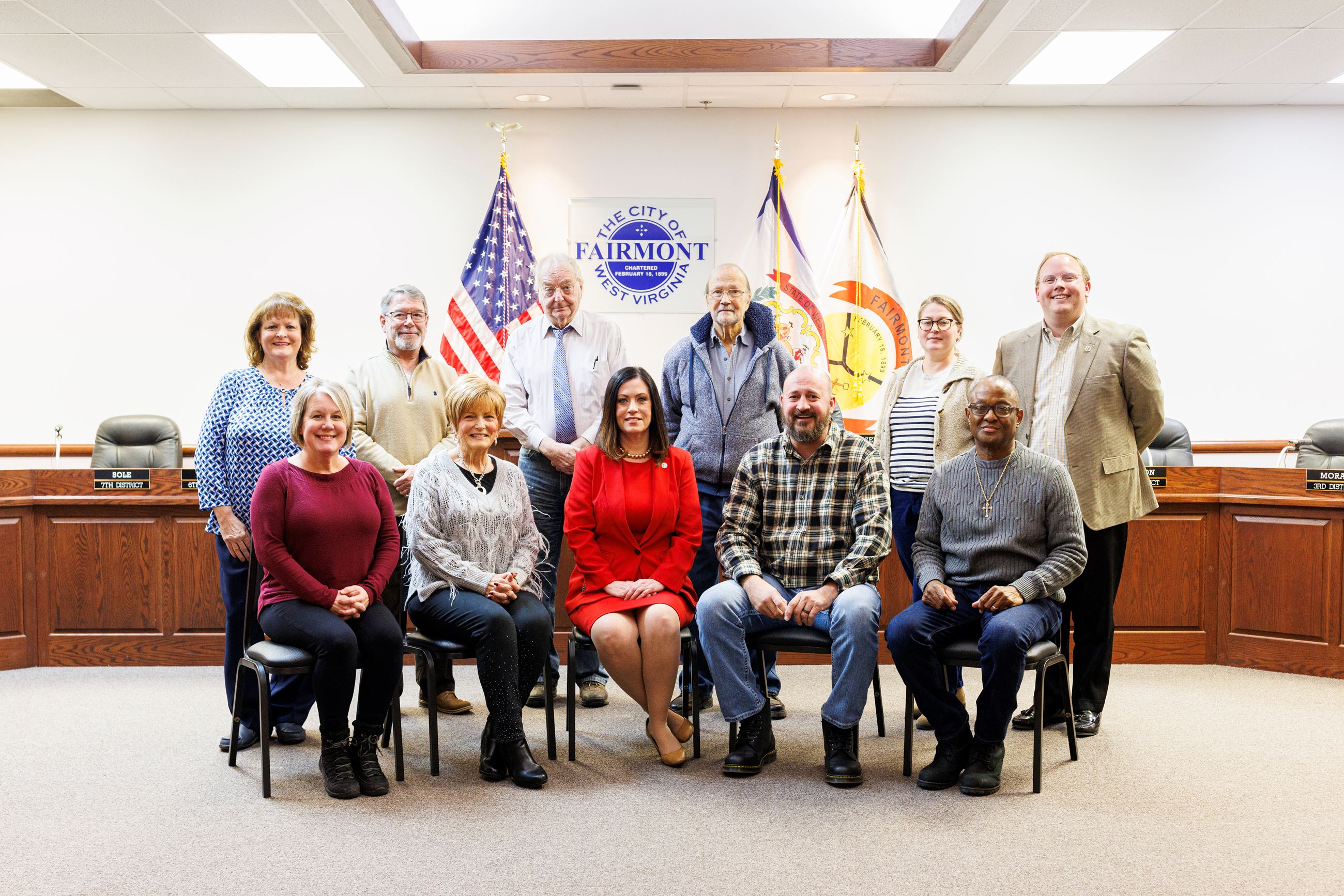A group picture of the 2025-26 Fairmont City Council posing in front of the council dais.